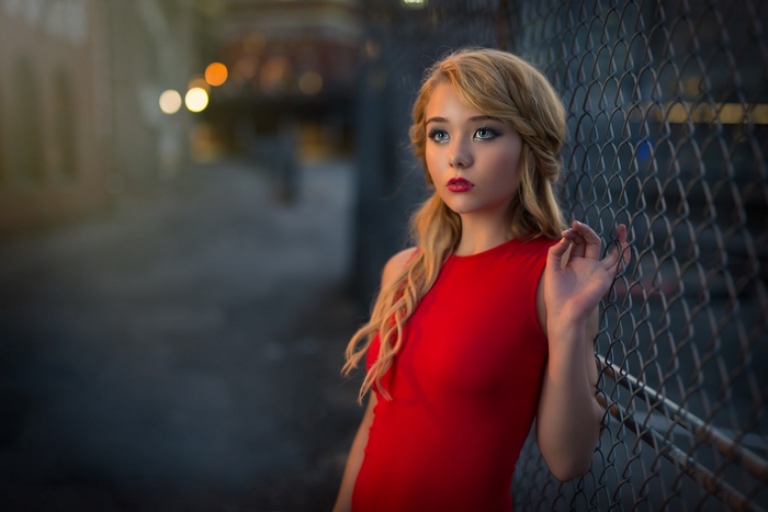 Woman in red dress leaning on a fence