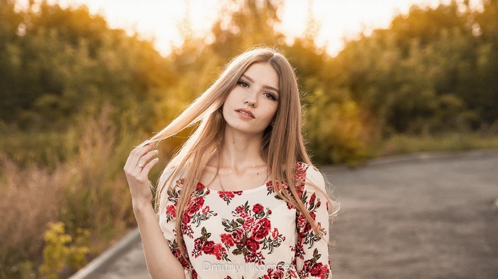 Woman with blonde hair holding her hair outdoors