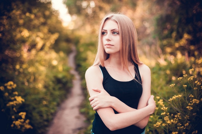 Woman with blonde hair in a black tank top outdoors
