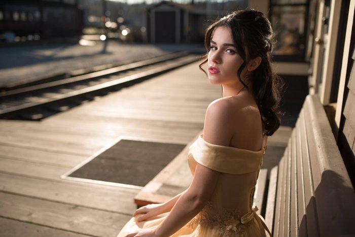 Woman in strapless dress sitting on a train platform