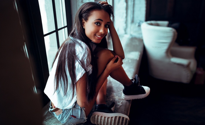 Woman in jean shorts sitting by a window