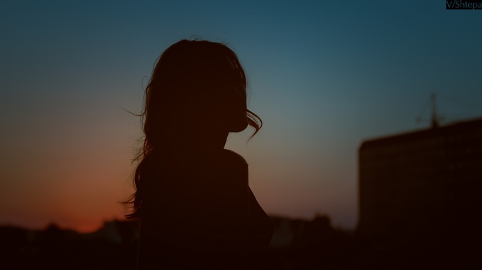 Silhouette of a woman against a sunset sky