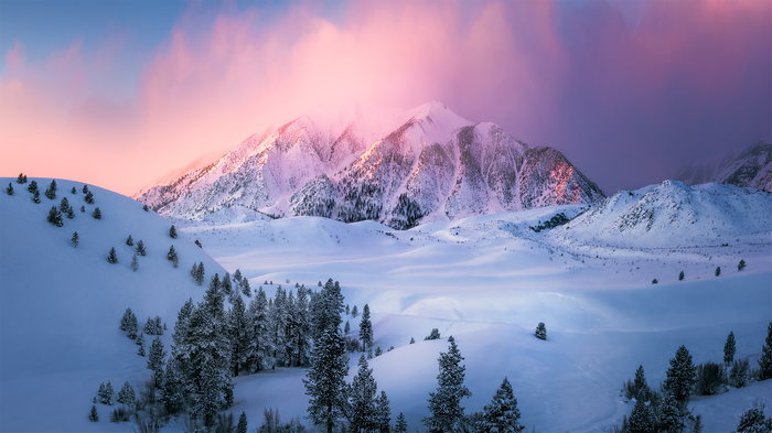 Snowy mountains at sunrise with pink clouds