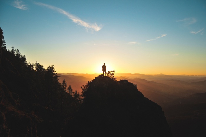 Man standing on mountain peak at sunrise