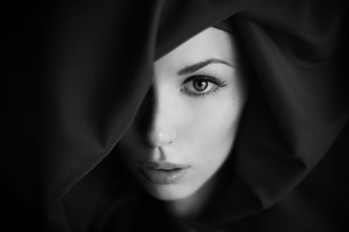 Monochrome portrait of a woman partially covered by dark fabric