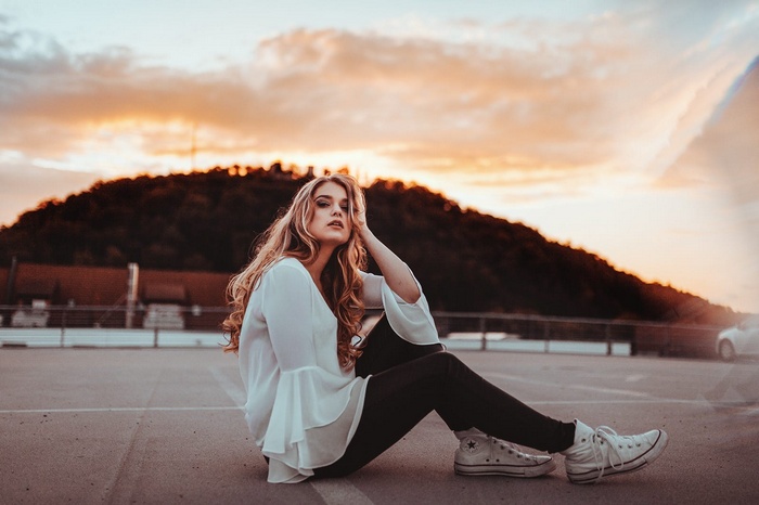 Woman in white shirt and leggings sitting at sunset