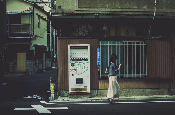 Woman looking at phone near vending machine in Japan