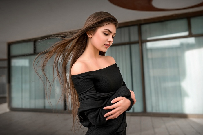 Woman with long brown hair wearing a black off-the-shoulder top