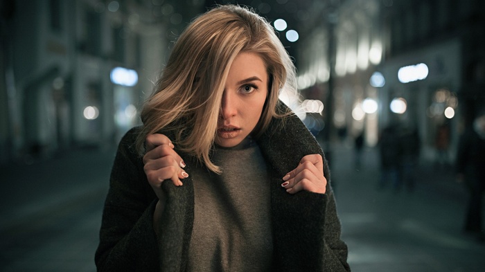 Woman in grey coat on a street at night