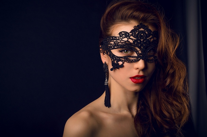 Woman wearing a black lace mask and earrings