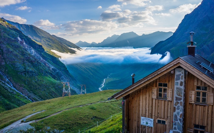 Wooden mountain hut with clouds and mountains