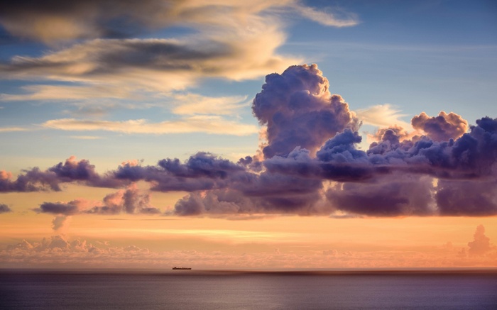 Ship on the ocean at sunset with dramatic clouds