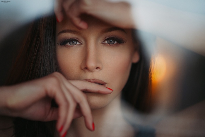 Woman with red nails and gray eyes, finger on lips