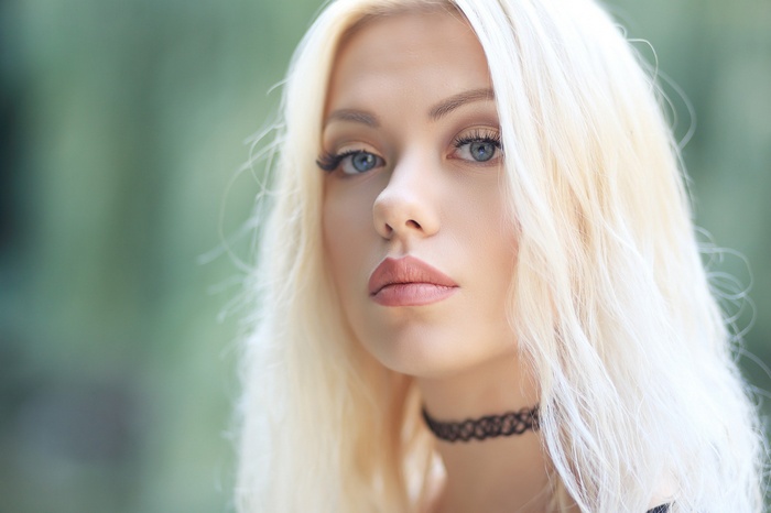 Woman with blonde hair and blue eyes wearing a choker