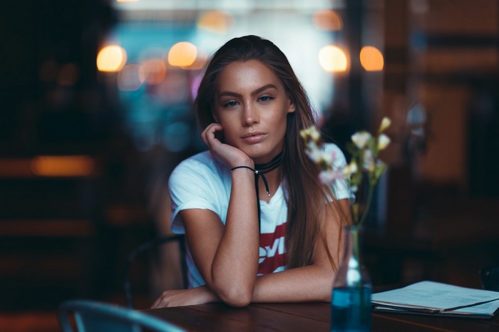 Woman with freckles wearing a white T-shirt at a table