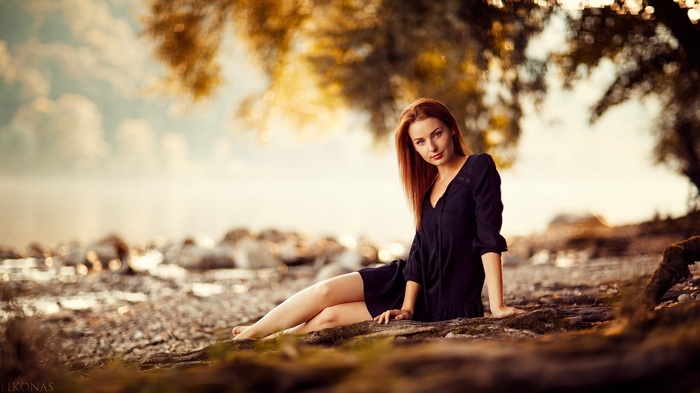 Woman in black dress sitting by the water