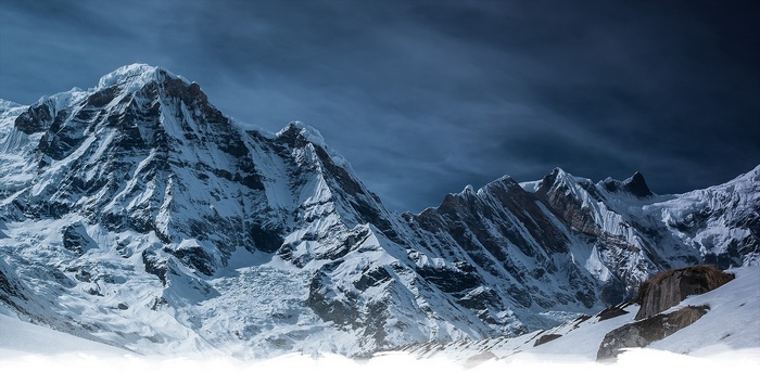 Snowy Annapurna mountain range under a dark sky