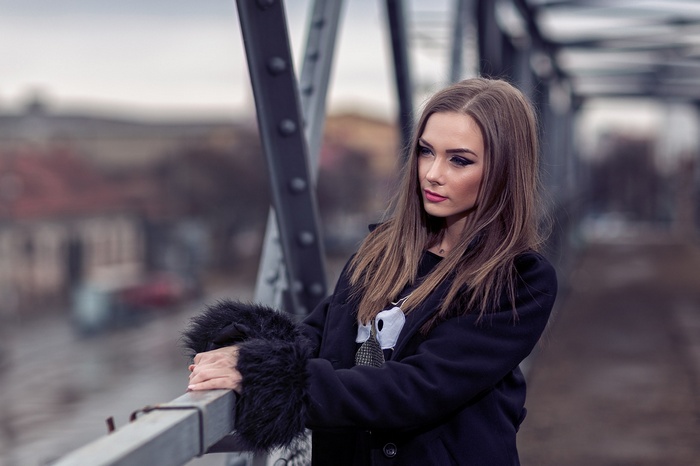 Woman in black coat on a bridge