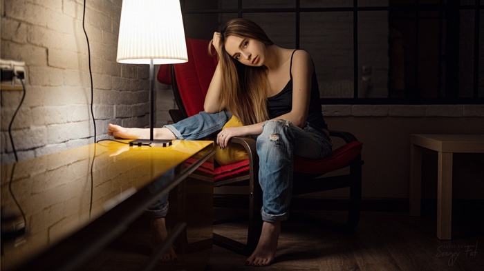 Woman in torn jeans sitting by a lamp