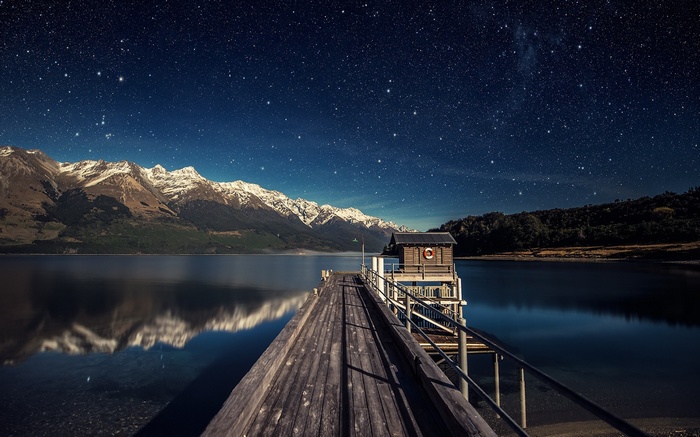 Wooden pier and boathouse under starry sky