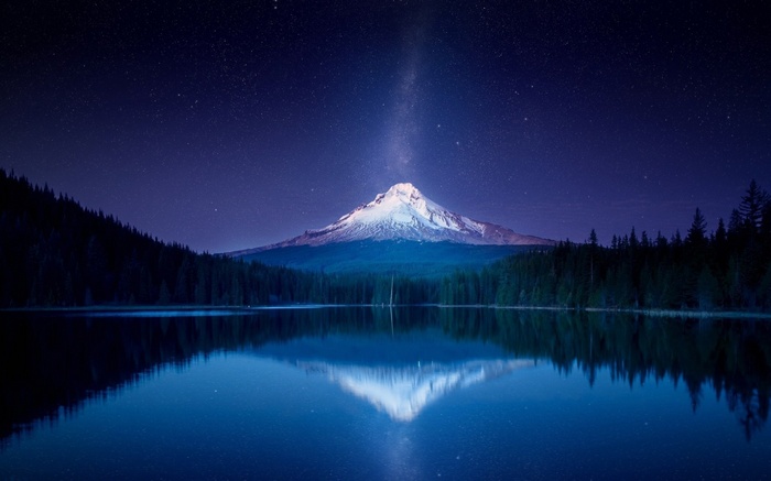 Snow-capped mountain under the Milky Way reflected in a lake