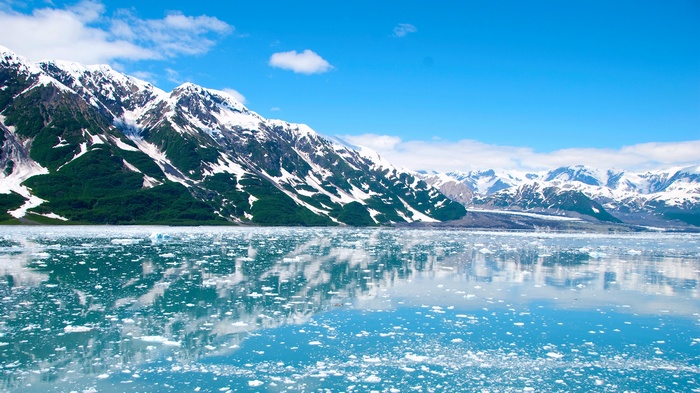 Snow-capped mountains reflected in icy water
