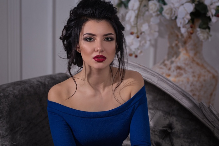 Woman in a blue dress sitting on a couch