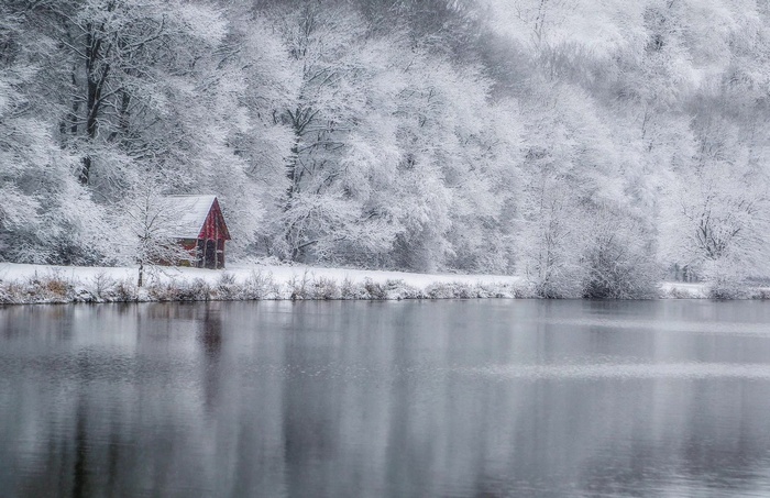 Red hut by a lake in winter snow
