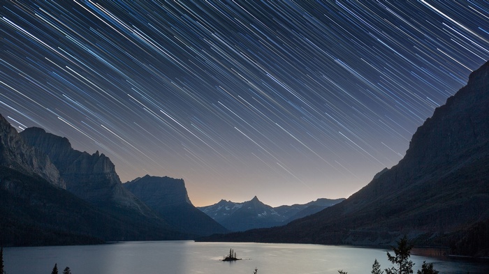 Star trails over a lake and mountains