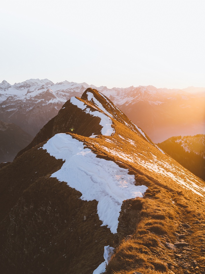 Person on a snowy mountain ridge at sunset