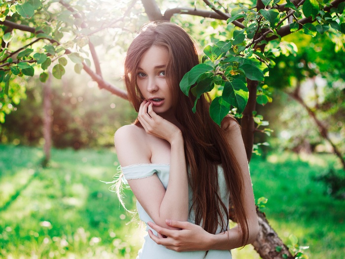 Young woman with long brown hair in a garden