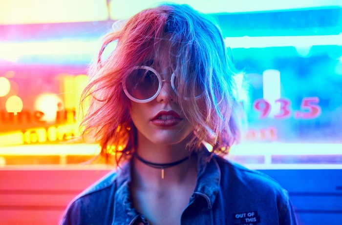 Woman with pink and blue hair wearing sunglasses and choker