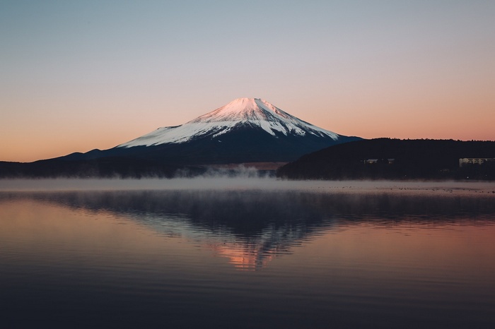 Mount Fuji reflected in a misty lake at sunrise