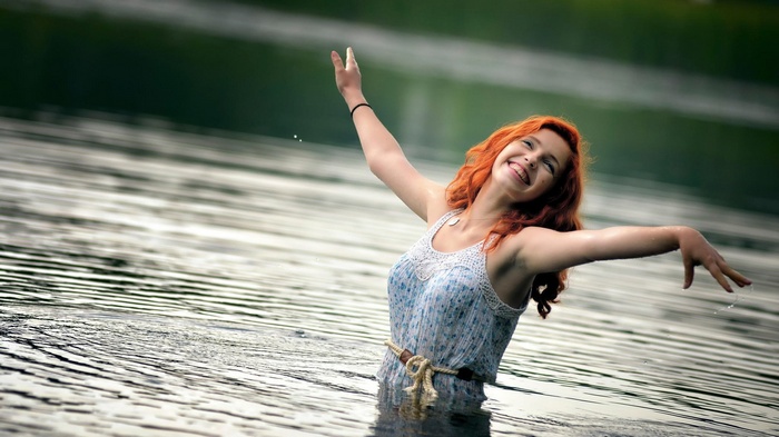 Woman with red hair in a dress in the water