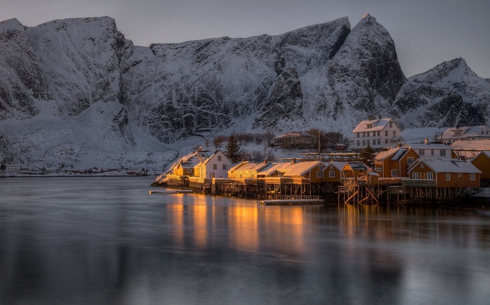 Snowy village with mountains and water reflection in Lofoten, Norway