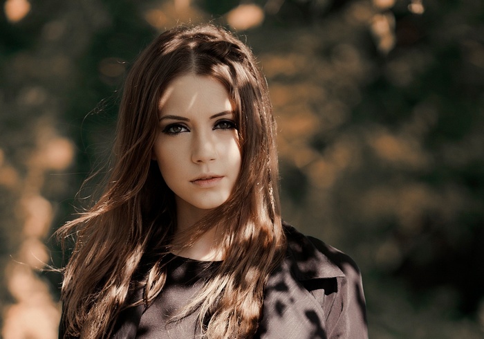 Woman with long brown hair and smoky eyes outdoors