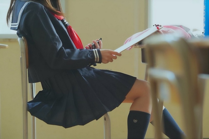 Schoolgirl in uniform sitting in a classroom