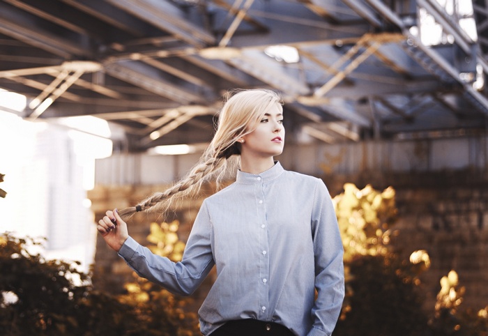 Woman with blonde braid outdoors under bridge