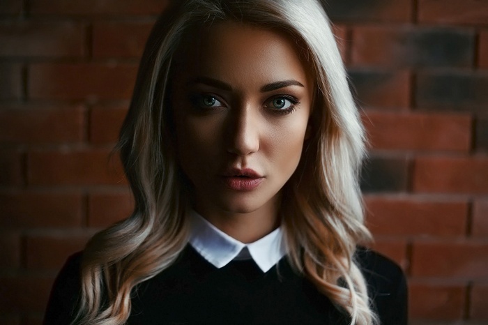 Woman with blonde hair in front of brick wall