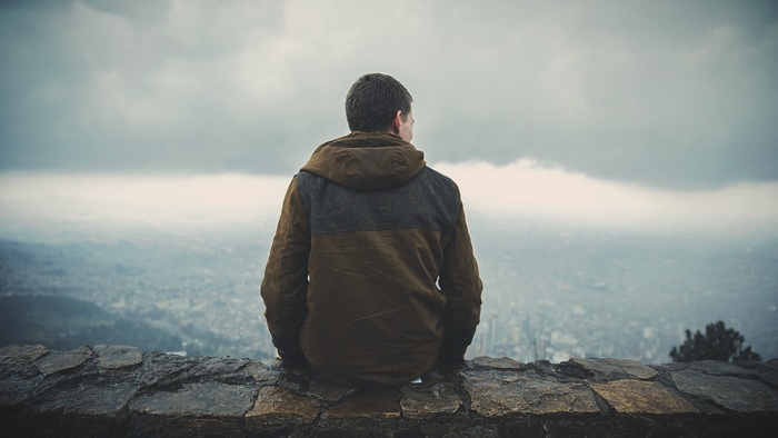 Man sitting on a stone wall overlooking a city