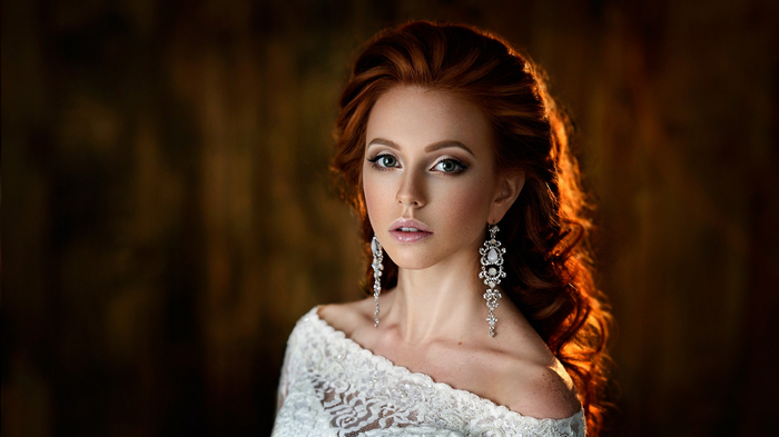 Redhead woman with elaborate earrings and white dress