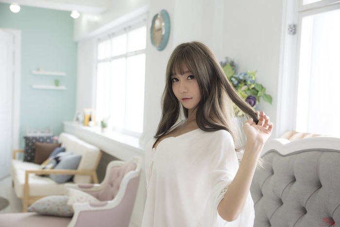 Asian woman with long brown hair in white clothing indoors