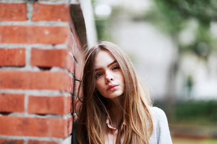 Young woman leaning against a brick wall