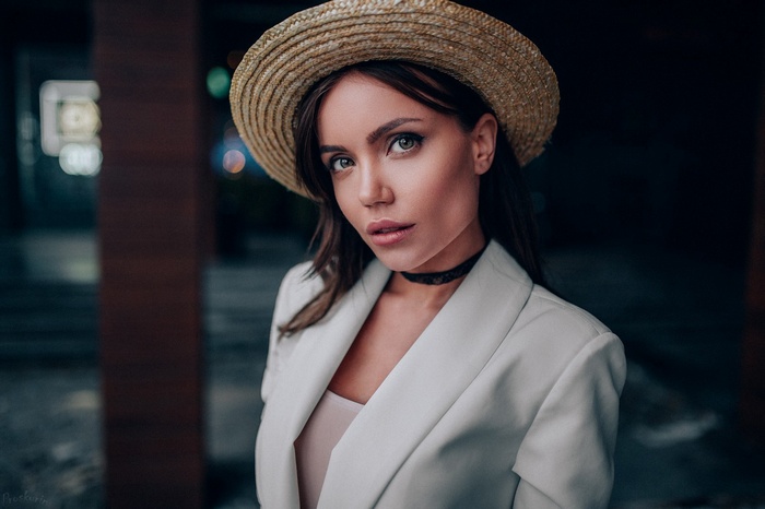 Woman wearing a straw hat and white blazer