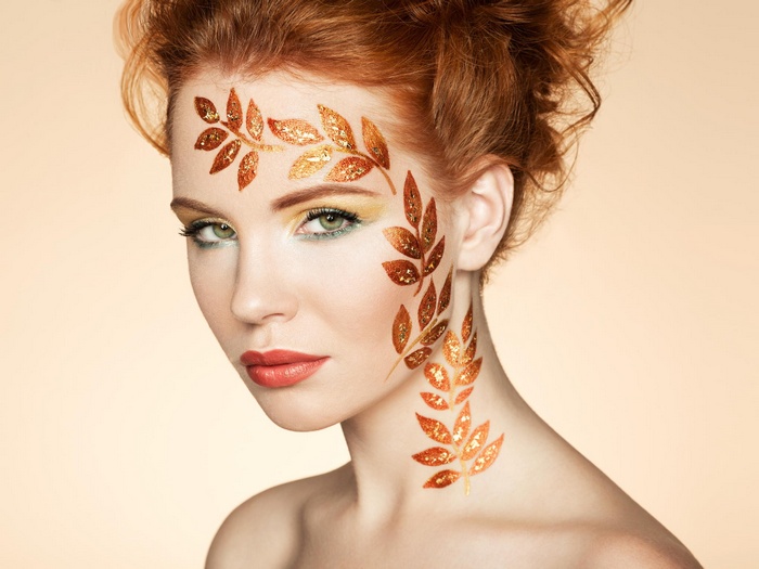 Woman with red hair and leaf face paint