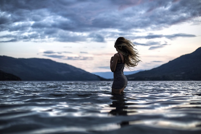 Woman in striped dress standing in water at dusk
