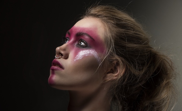 Woman with pink and white face paint and septum piercing