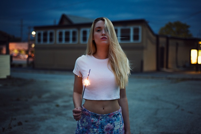 Woman holding a sparkler outdoors at dusk