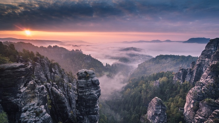 Misty mountain valley at sunrise with rock formations