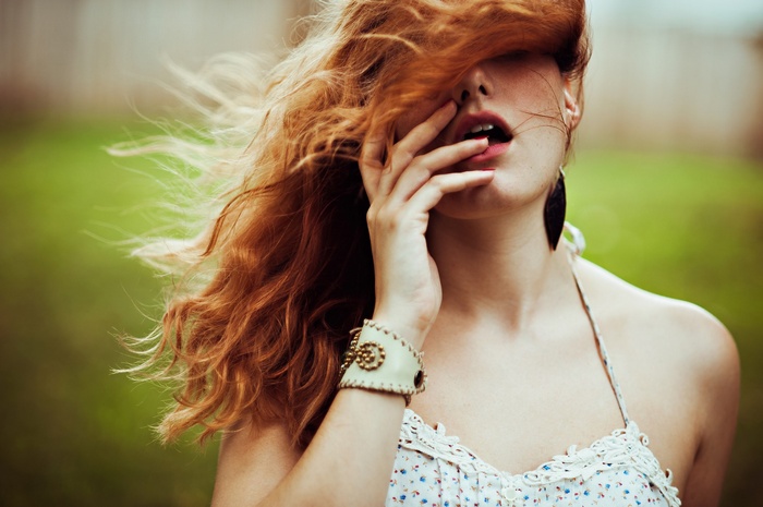 Redhead woman with hair in face outdoors